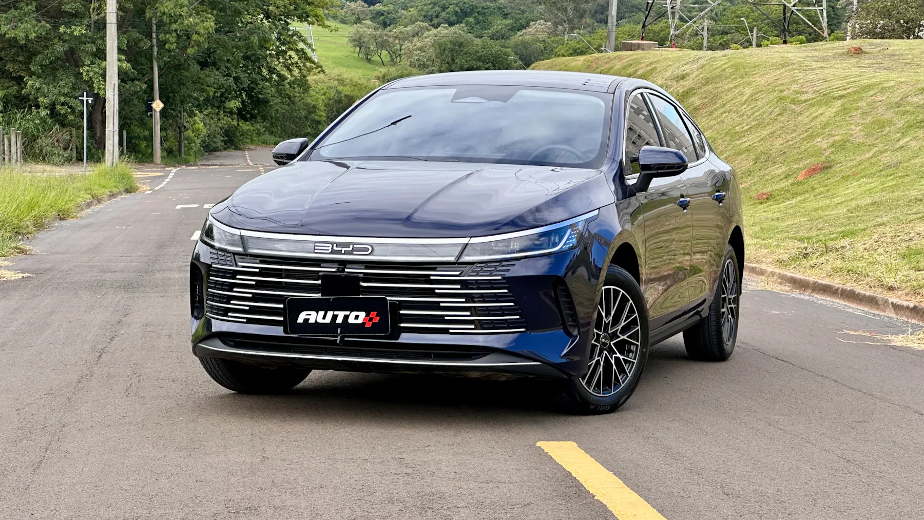 Híbrido BYD King GS azul parado de frente com árvores ao fundo 