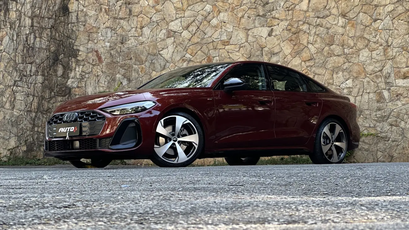 Audi A5 Performance S Edition vermelho parado de frente com muro de pedras ao fundo. A marca de luxo batiza os modelos com siglas