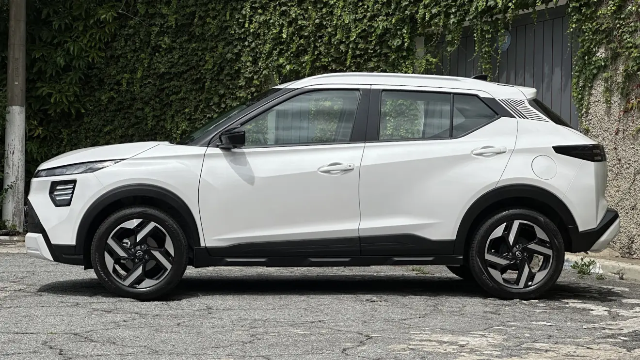 Nissan Kait Exclusive branco parado de lateral com muro de plantas ao fundo