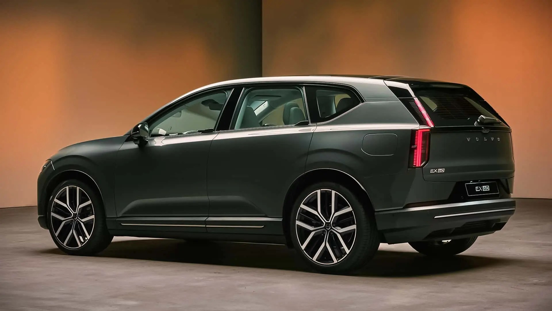 Volvo EX60 cinza visto de trás e com lanternas acesas