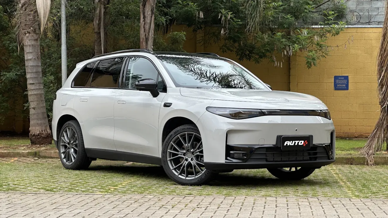 Leapmotor C10 REEV branco parado de dianteira com muro amarelo e plantas ao fundo