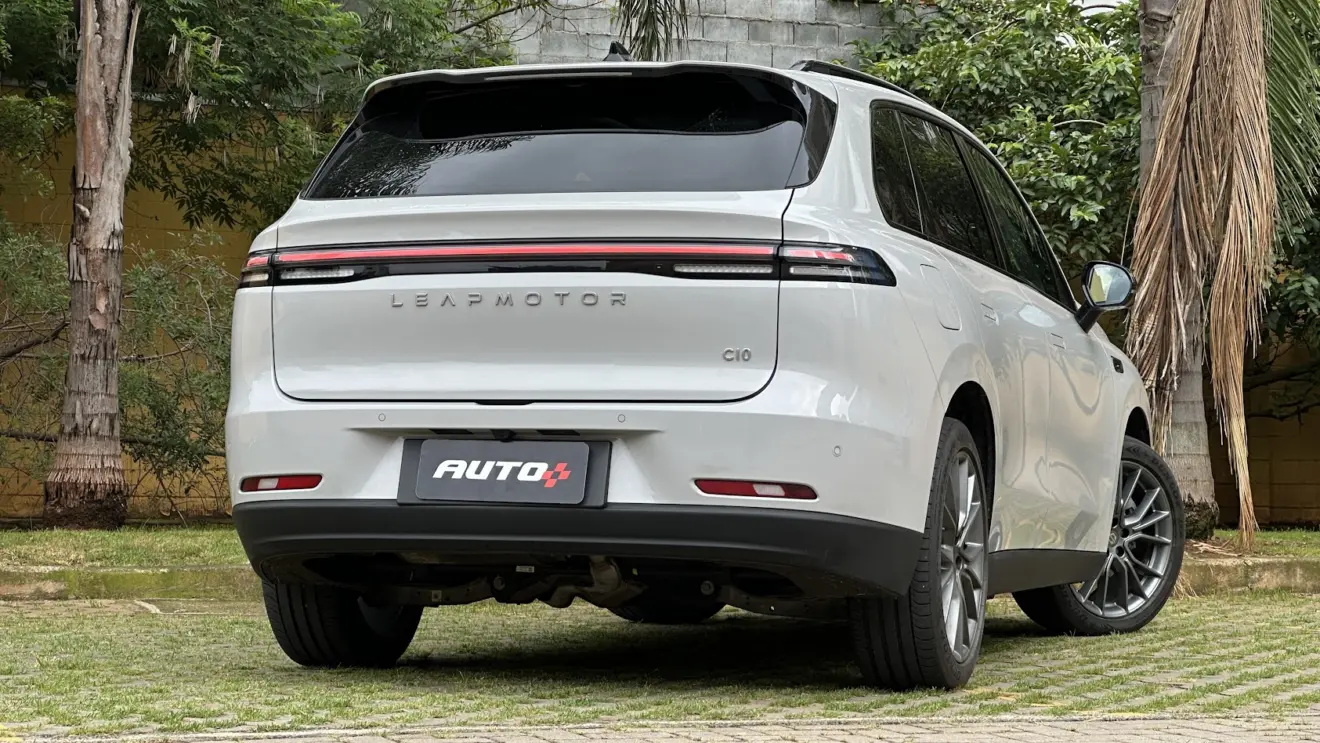 Leapmotor C10 REEV branco parado de traseira com plantas ao fundo