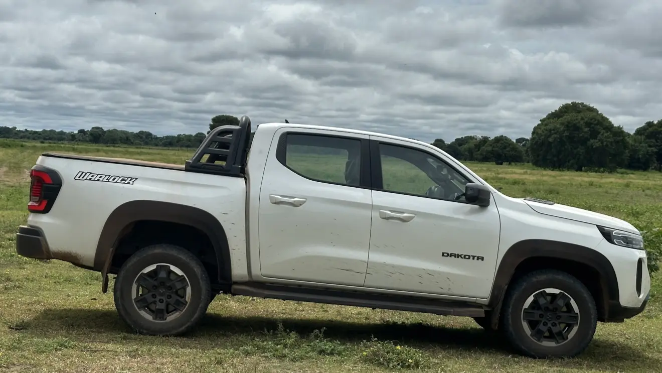 Caminhonete Ram Dakota Warlock branca parada de lateral com árvores ao fundo