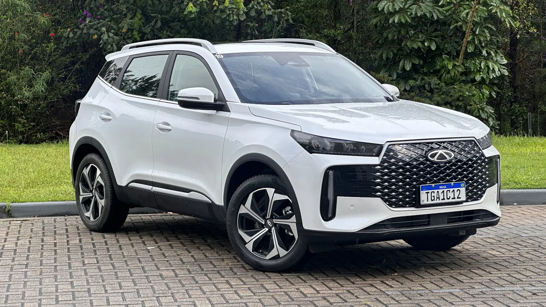 Caoa Chery Tiggo 5X Pro branco de frente em um mato hev híbrido