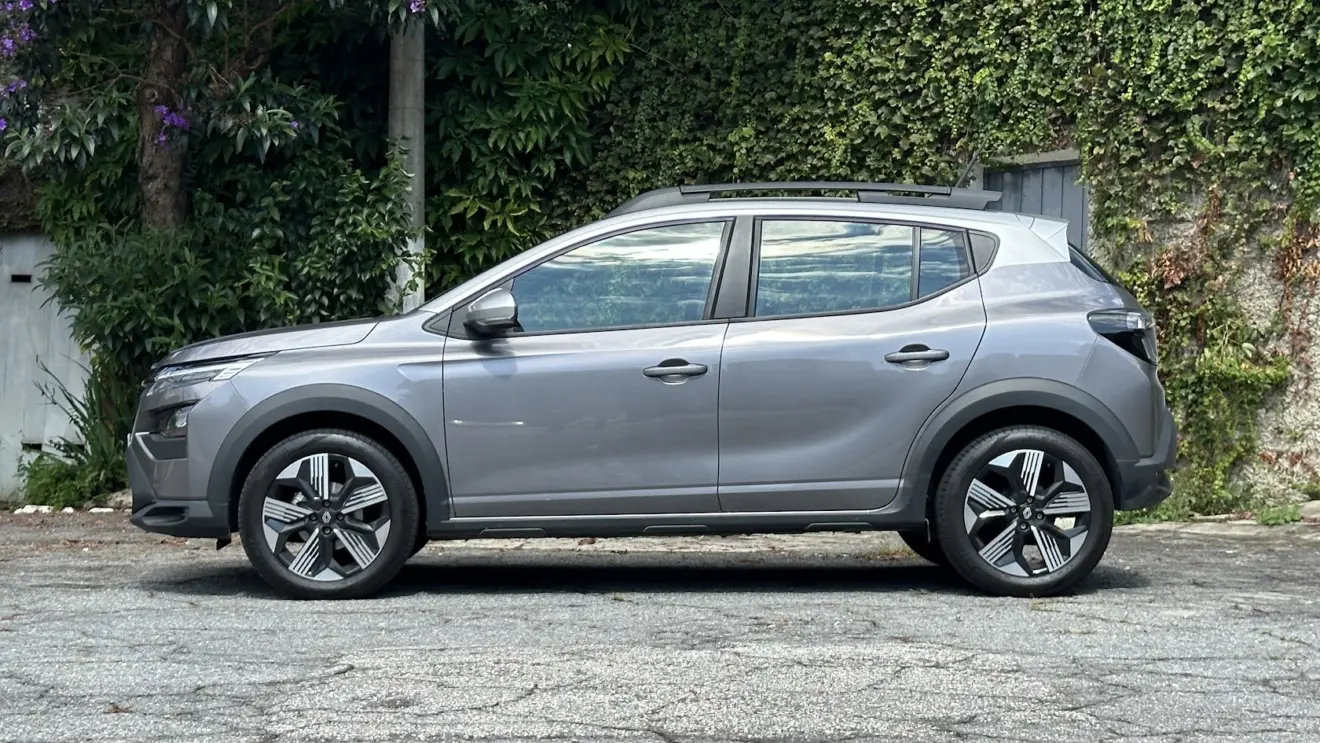 Renault Kardian cinza parado de lateral com muro e plantas ao fundo 