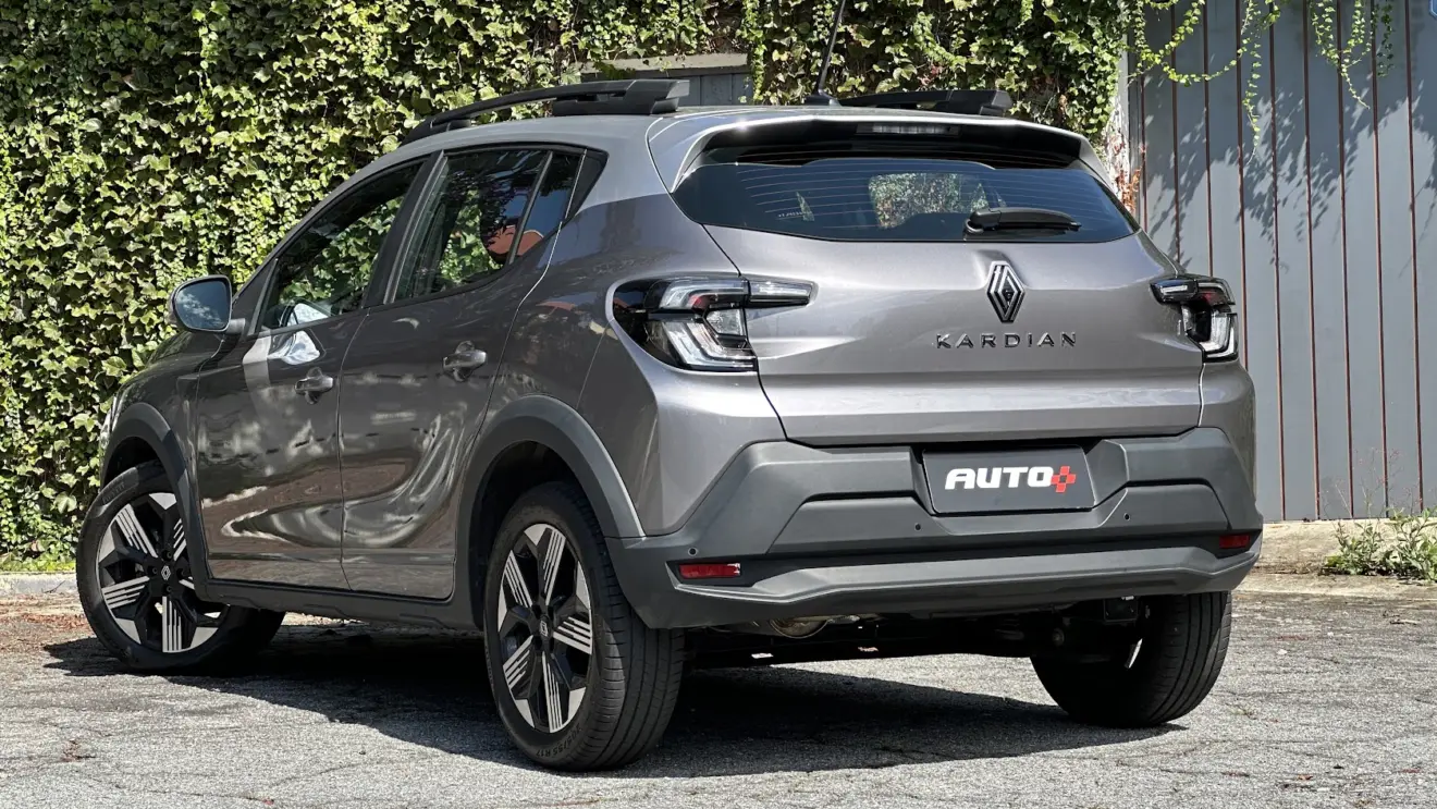 Renault Kardian Techno cinza parado de traseira com muro de plantas ao fundo