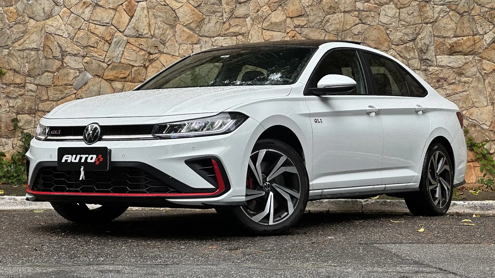 Volkswagen Jetta GLI 350 TSI branco parado de frente com muro de pedras ao fundo