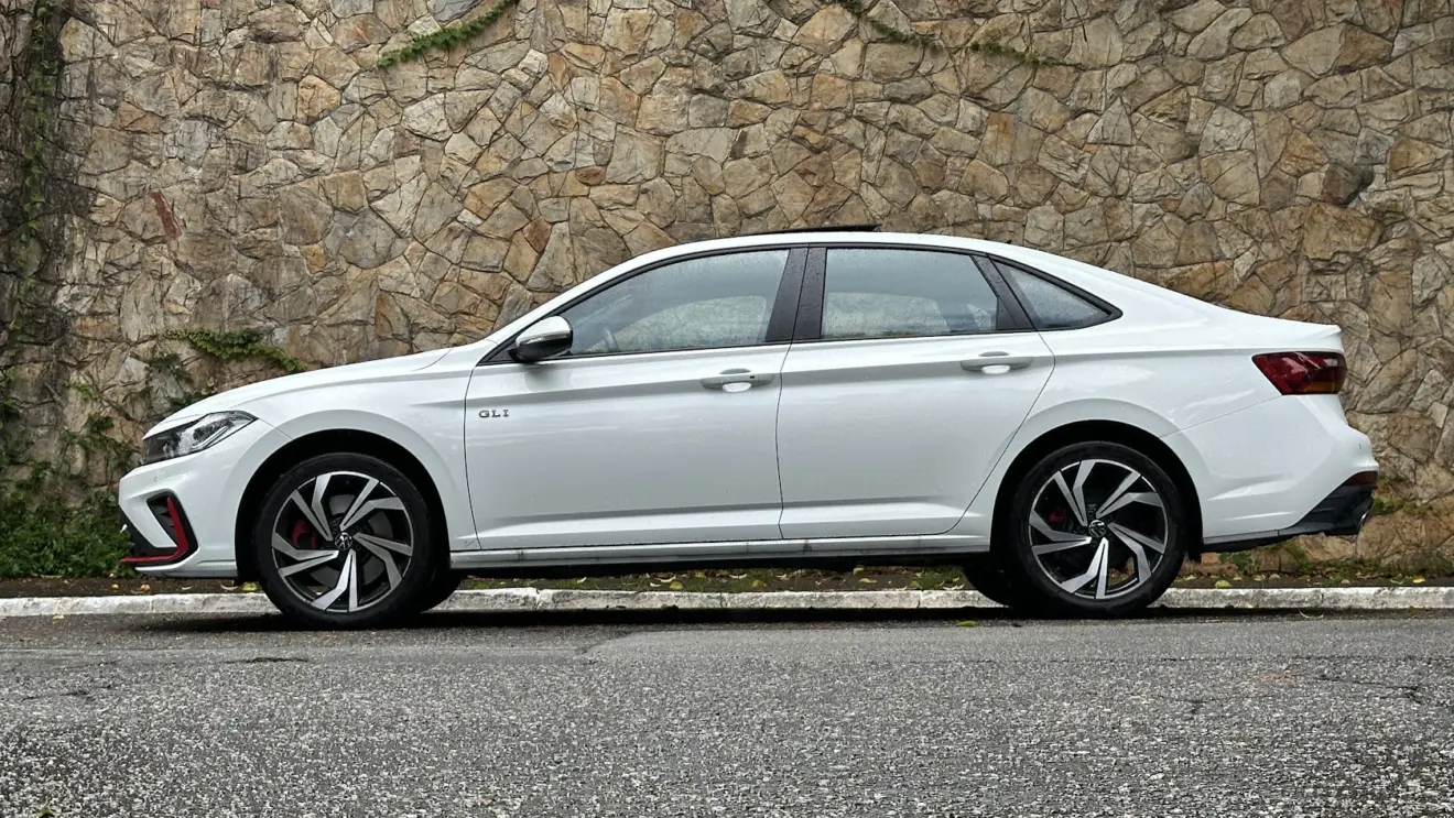 Volkswagen Jetta GLI 350 TSI parado de lateral com muro de pedras ao fundo