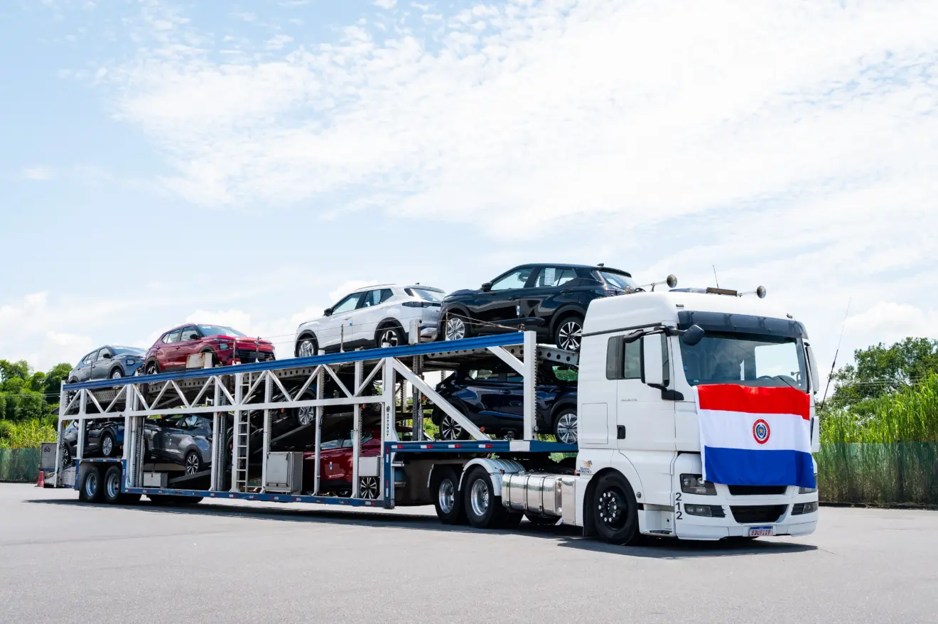 Carreta branca repleta de Nissan Kait vista de frente