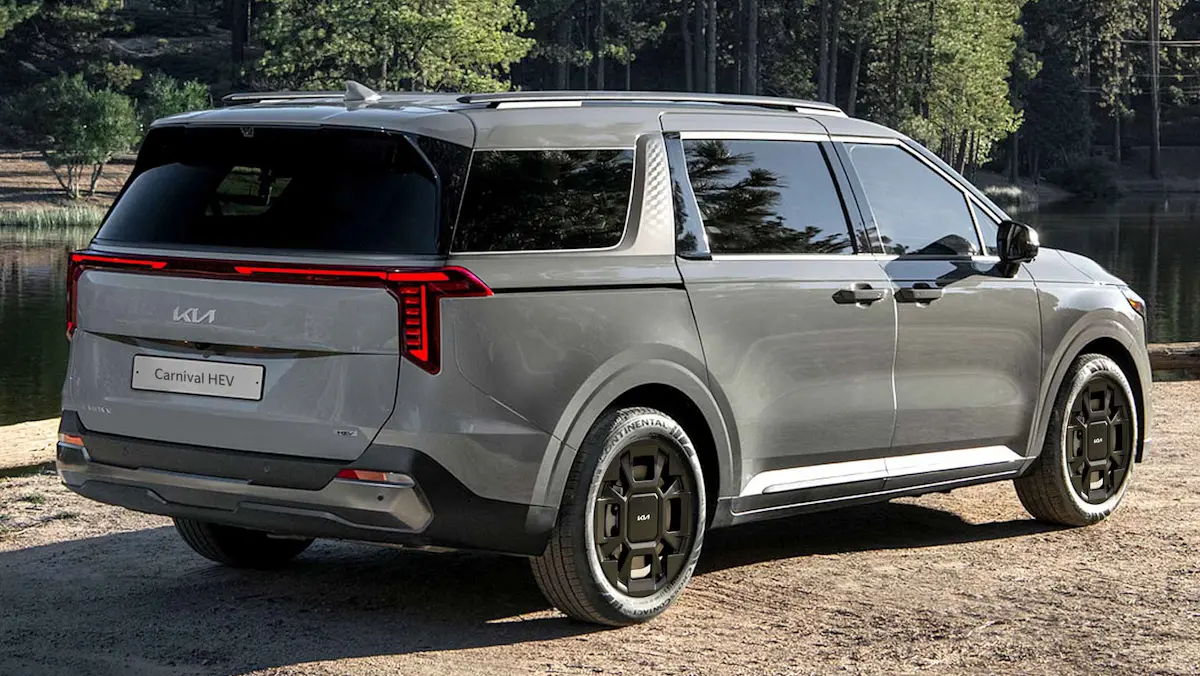 Kia Carnival HEV híbrida prata de traseira em cascalho