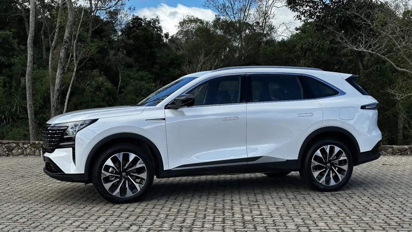 Caoa Changan CS75 branco parado de lateral com árvores ao fundo