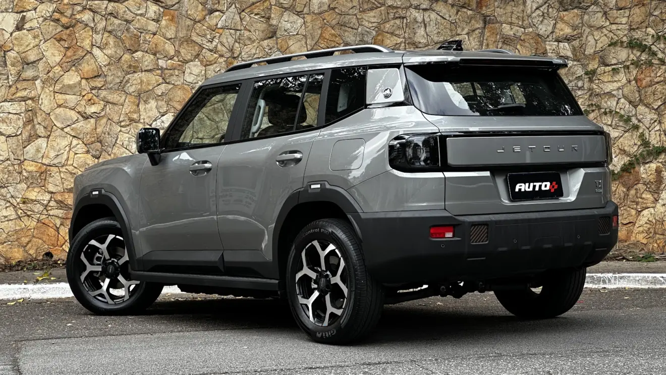 Jetour T1 Advance parado de traseira com muro de pedras ao fundo