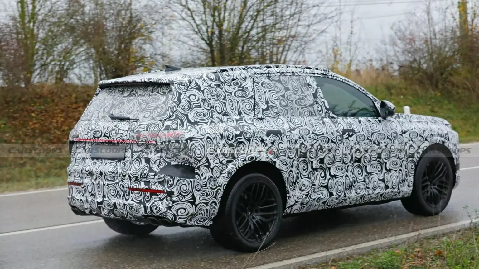 Protótipo do novo Audi SQ7, visto de trás, com camuflagem preta e branca e árvores ao redor