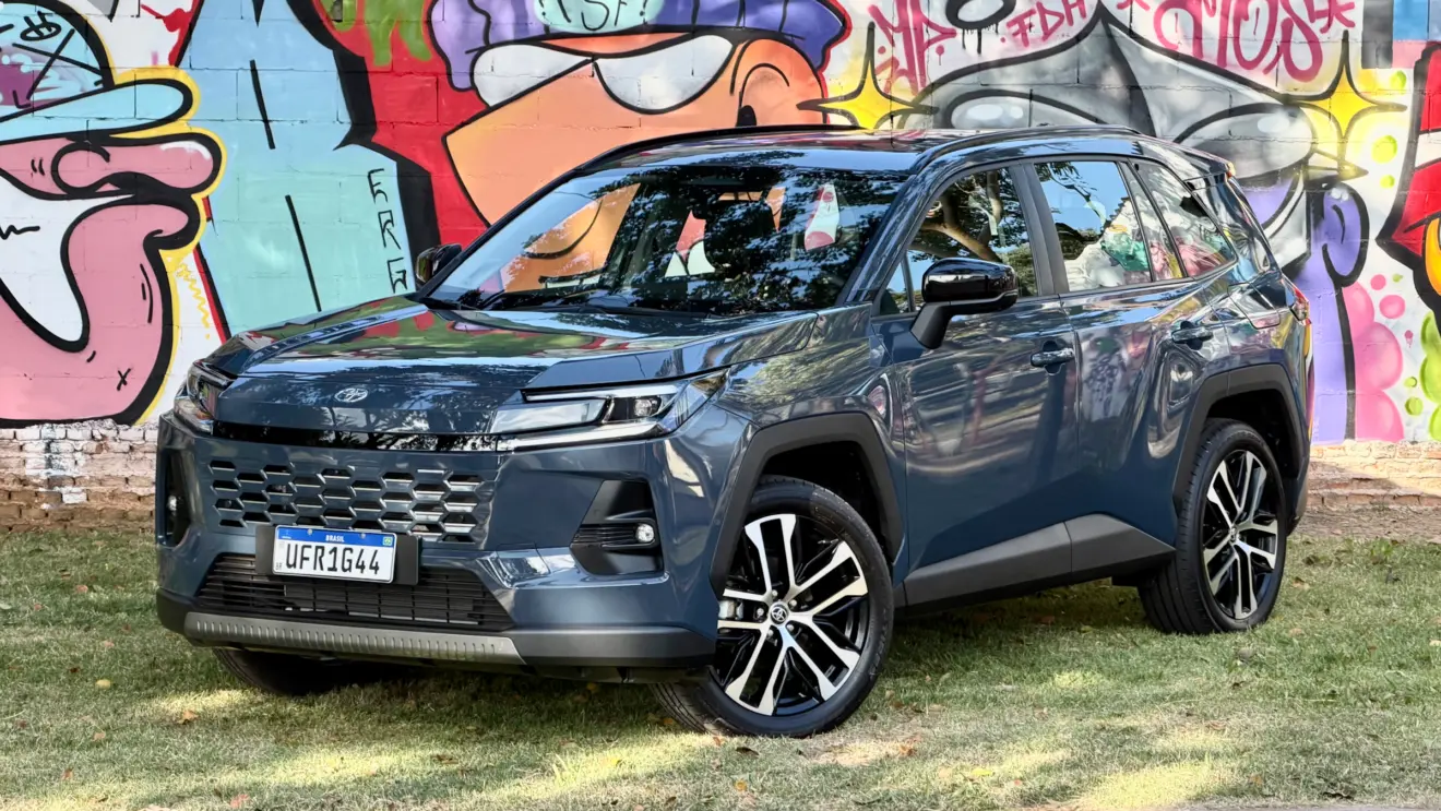 Toyota RAV4 azul de frente com um muro com grafitti atrás