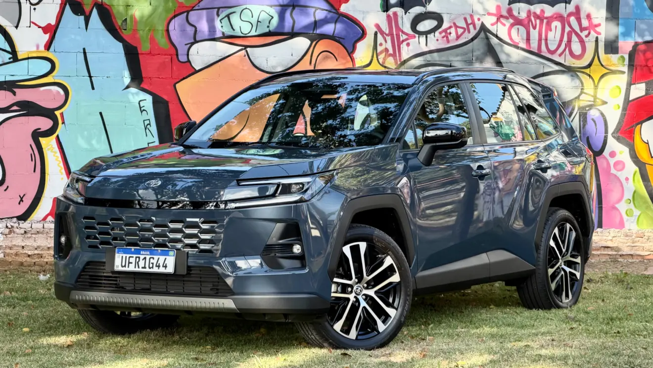 Toyota RAV4 azul de frente com um muro com grafitti atrás