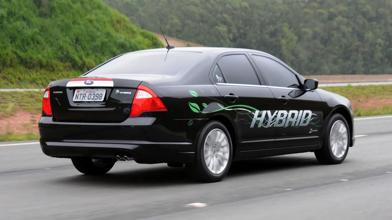 Ford Fusion Hybrid preto de traseira andando na estrada