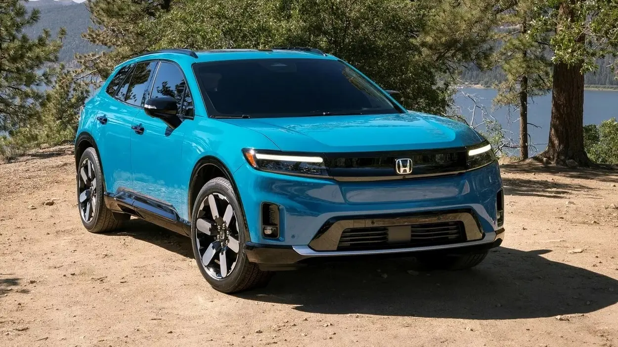 Honda Prologue azul de frente estacionado na areia com árvores ao fundo