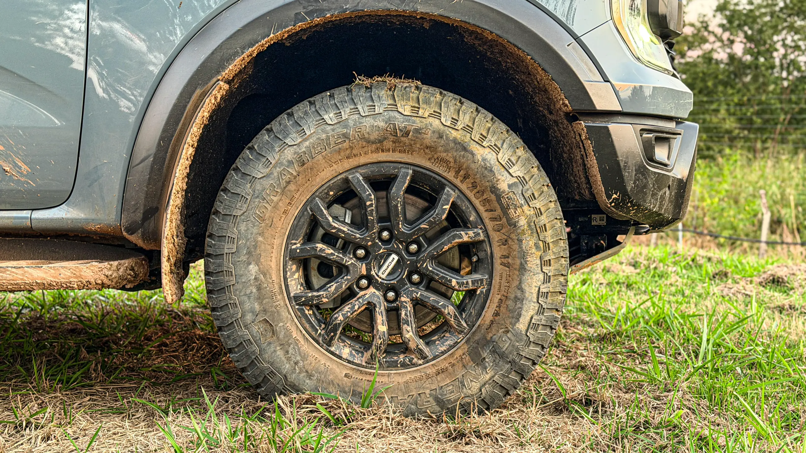 Ford Ranger Raptor suja de barro e terra estática na grama na cor Cinza Interlagos