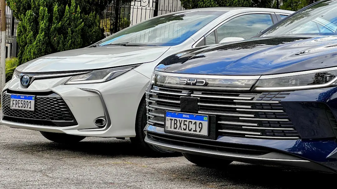 Detalhe frontal do Toyota Corolla Altis Premium branco e do BYD King GS Azul de frente