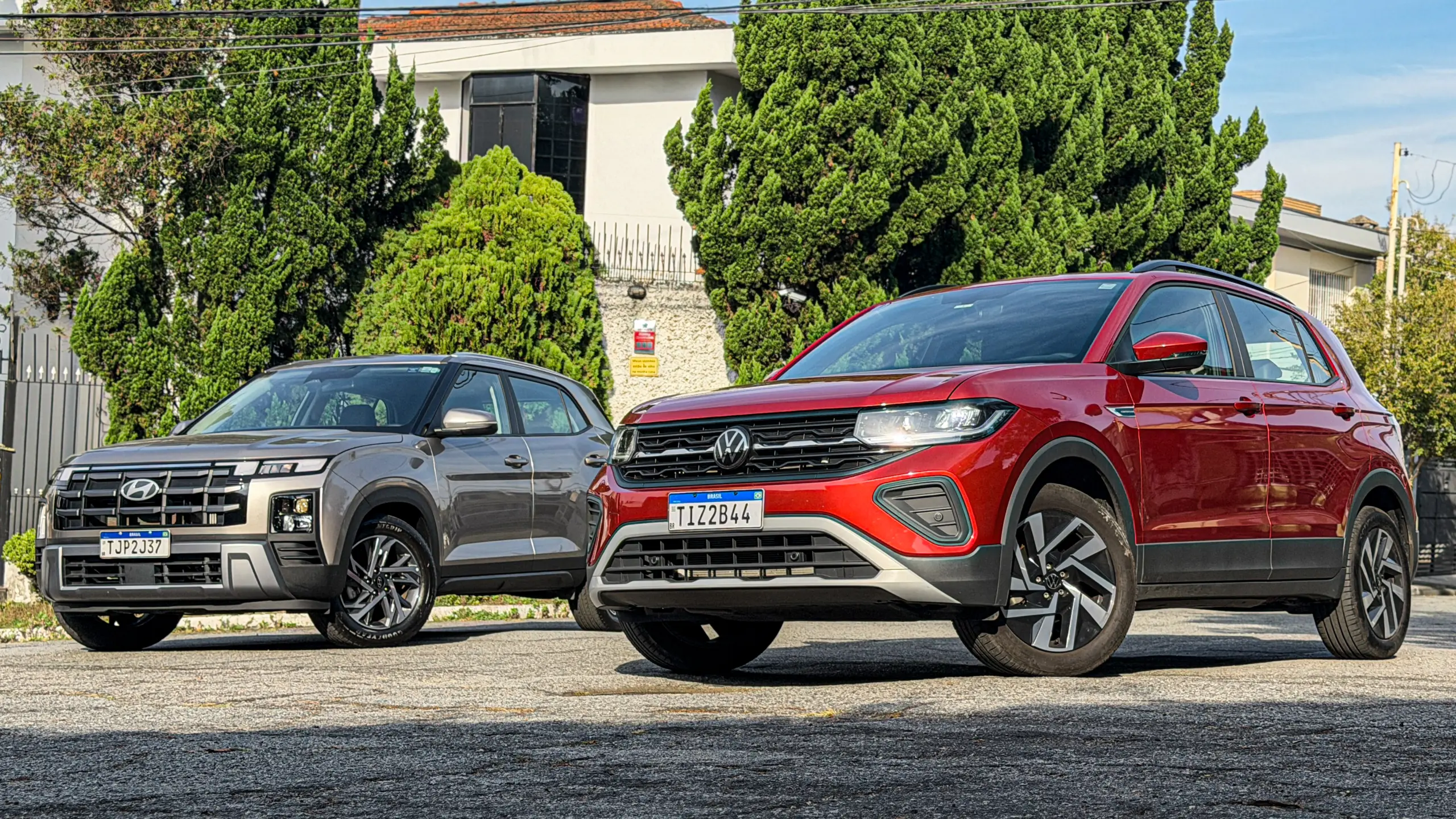 Volkswagen T-Cross Comfortiline Vermelho Sunset ao lado do Hyundai Creta Limited (na cor Cinza Silk estático