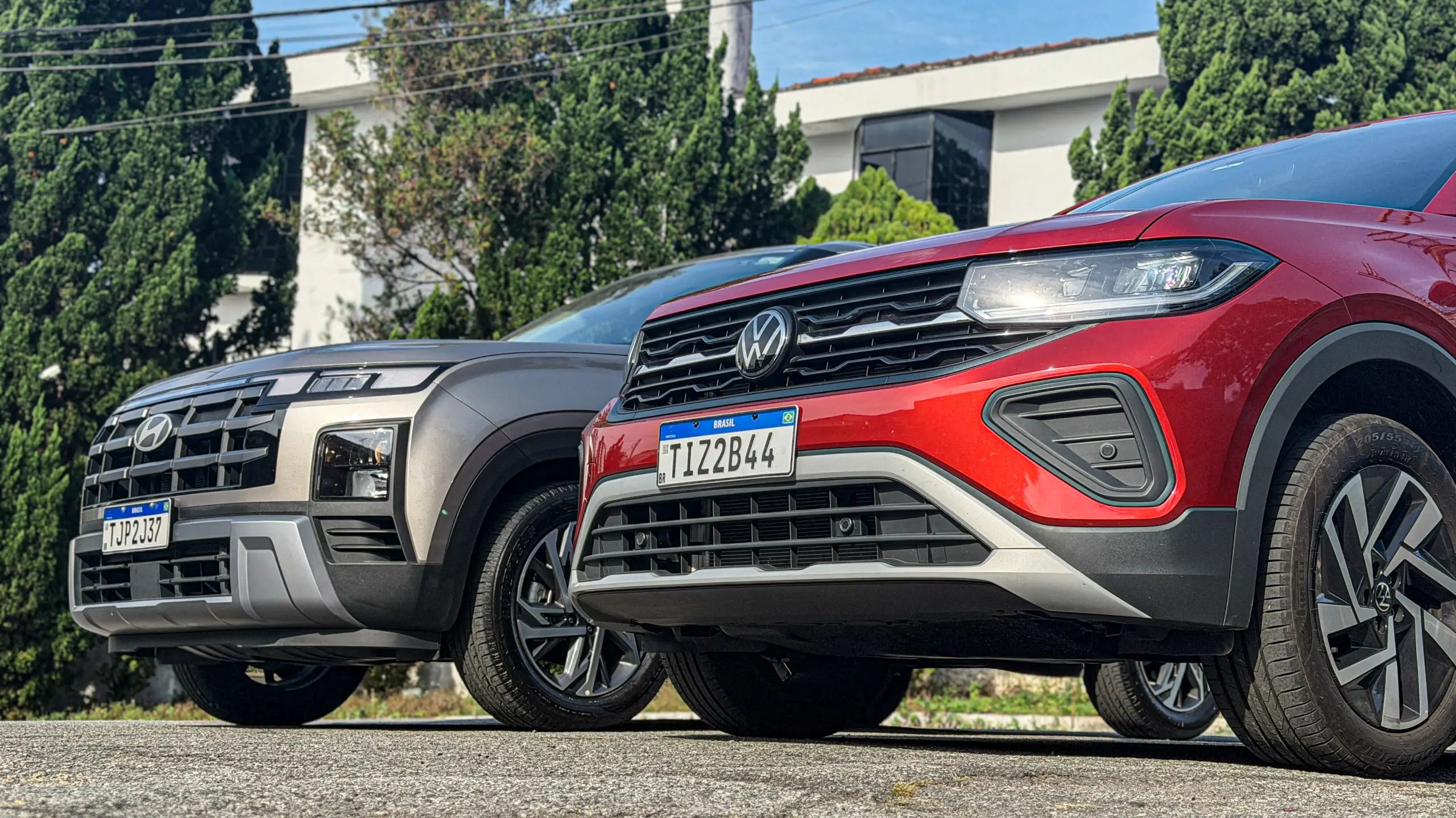Volkswagen T-Cross Comfortiline Vermelho Sunset ao lado do Hyundai Creta Limited (na cor Cinza Silk estático