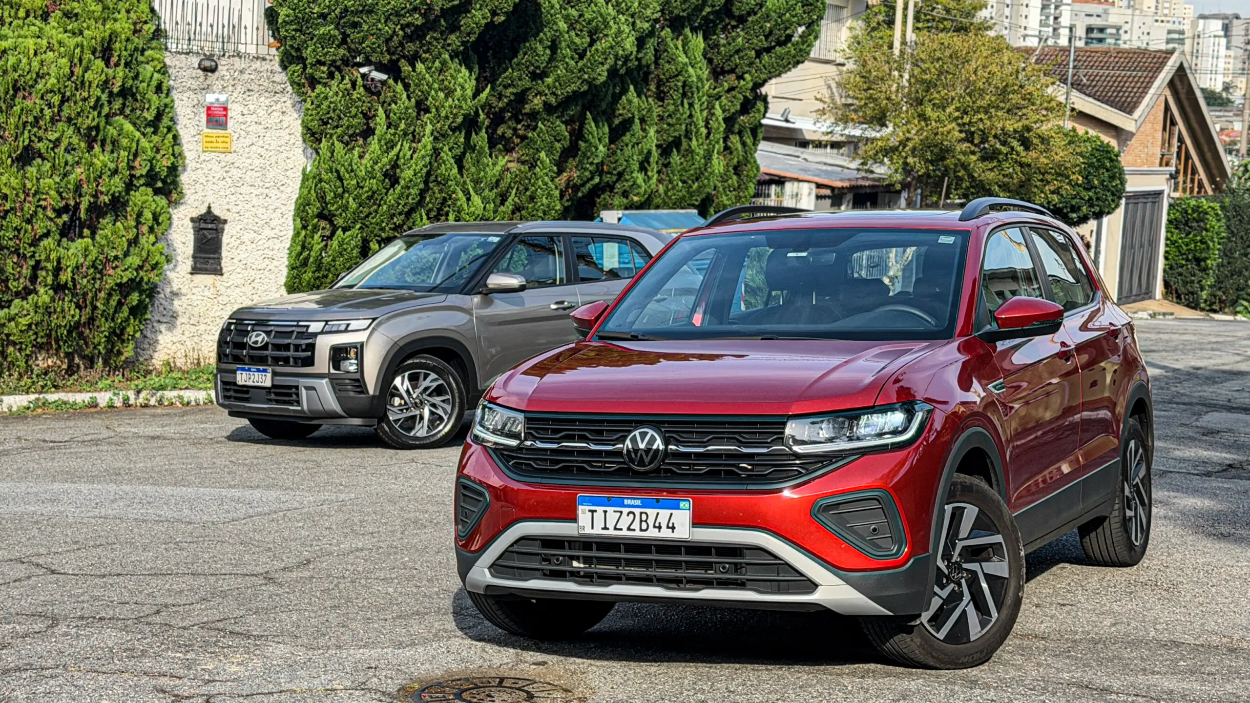 Volkswagen T-Cross Comfortiline Vermelho Sunset ao lado do Hyundai Creta Limited (na cor Cinza Silk estático
