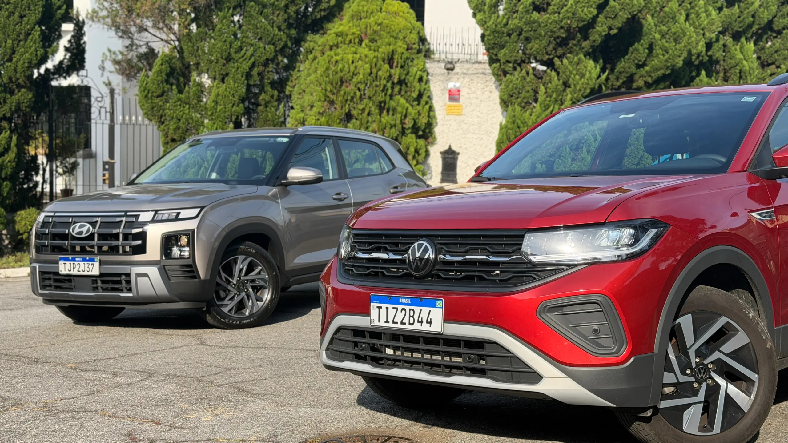 Volkswagen T-Cross Comfortiline Vermelho Sunset ao lado do Hyundai Creta Limited (na cor Cinza Silk estático