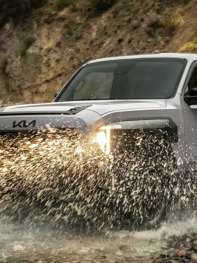 Kia Tasman cinza andando na água de frente