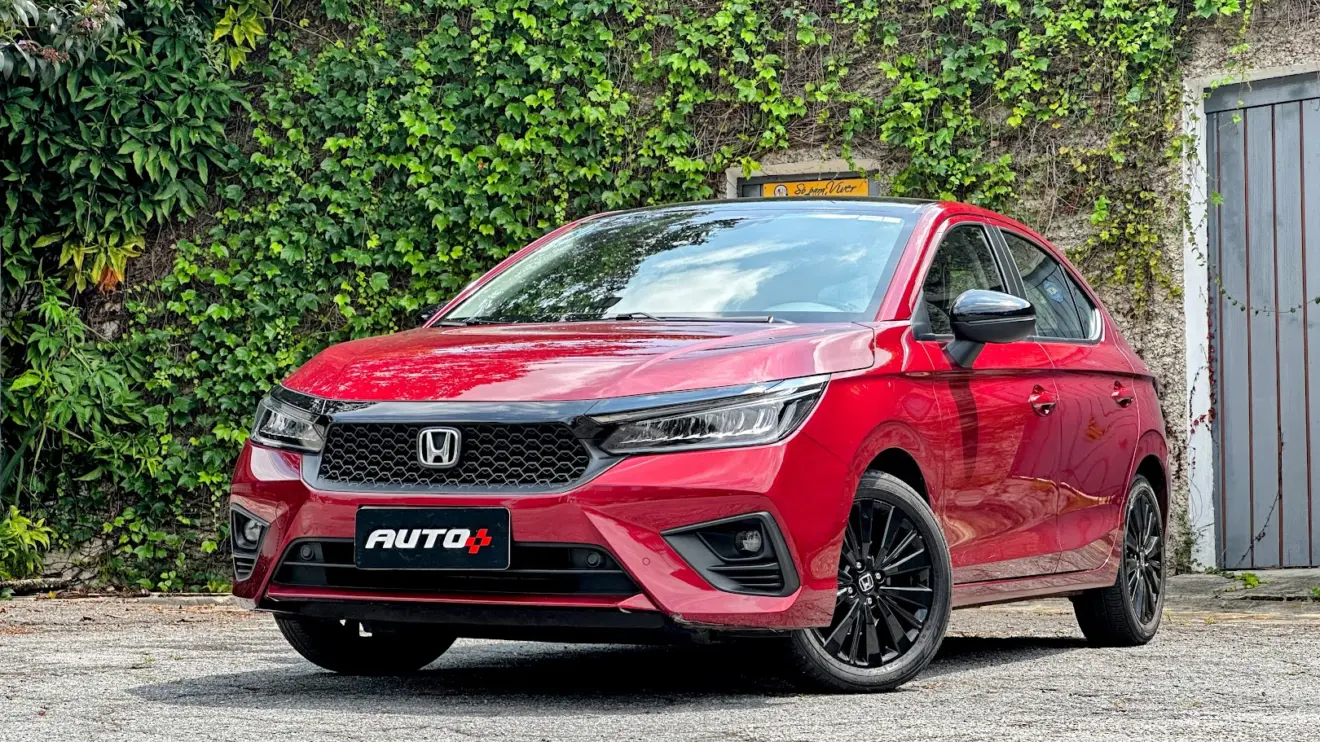 Honda City Hatchback Touring Sport vermelho parado de frente com muro de plantas ao fundo
