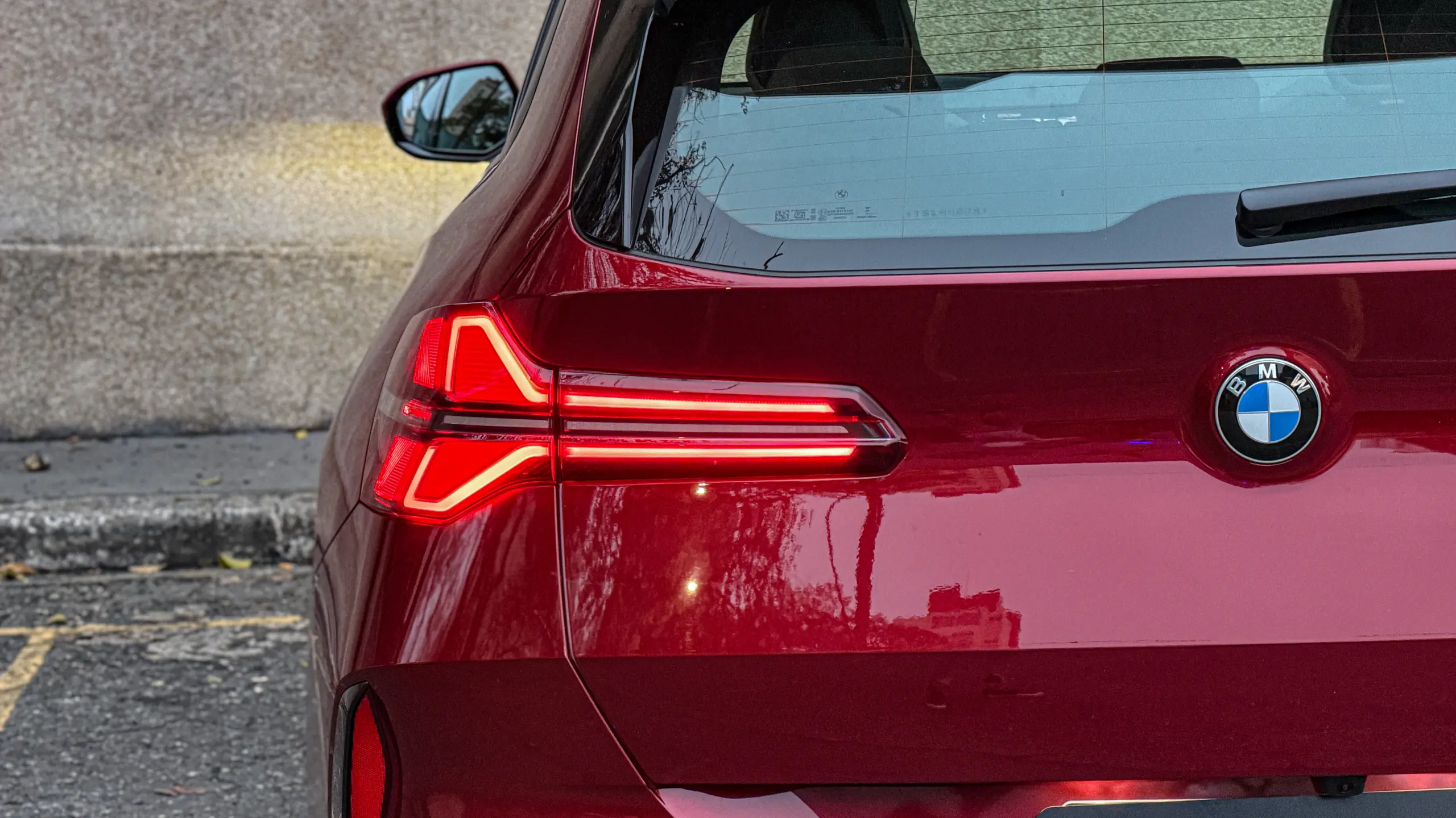 Detalhes do BMW X3 estático na cor Vermelho Fire no asfalto para teste e avaliação