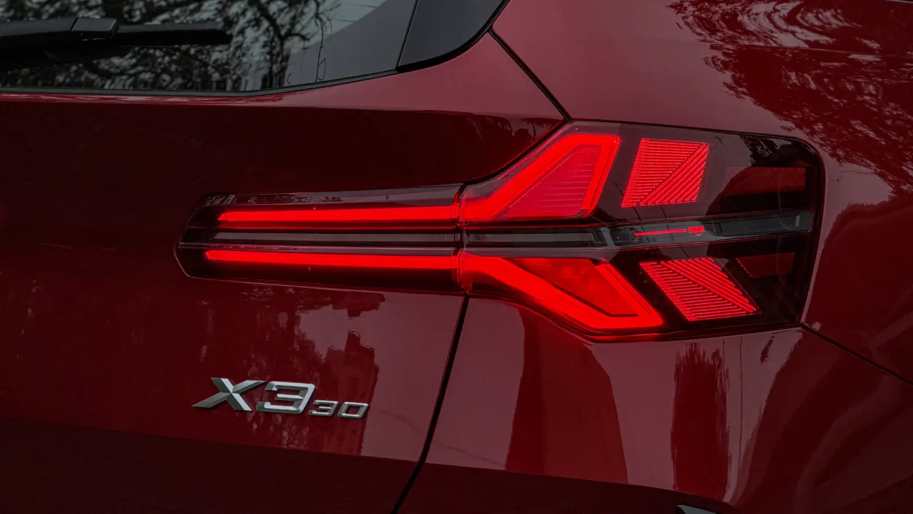 Detalhes do BMW X3 estático na cor Vermelho Fire no asfalto para teste e avaliação