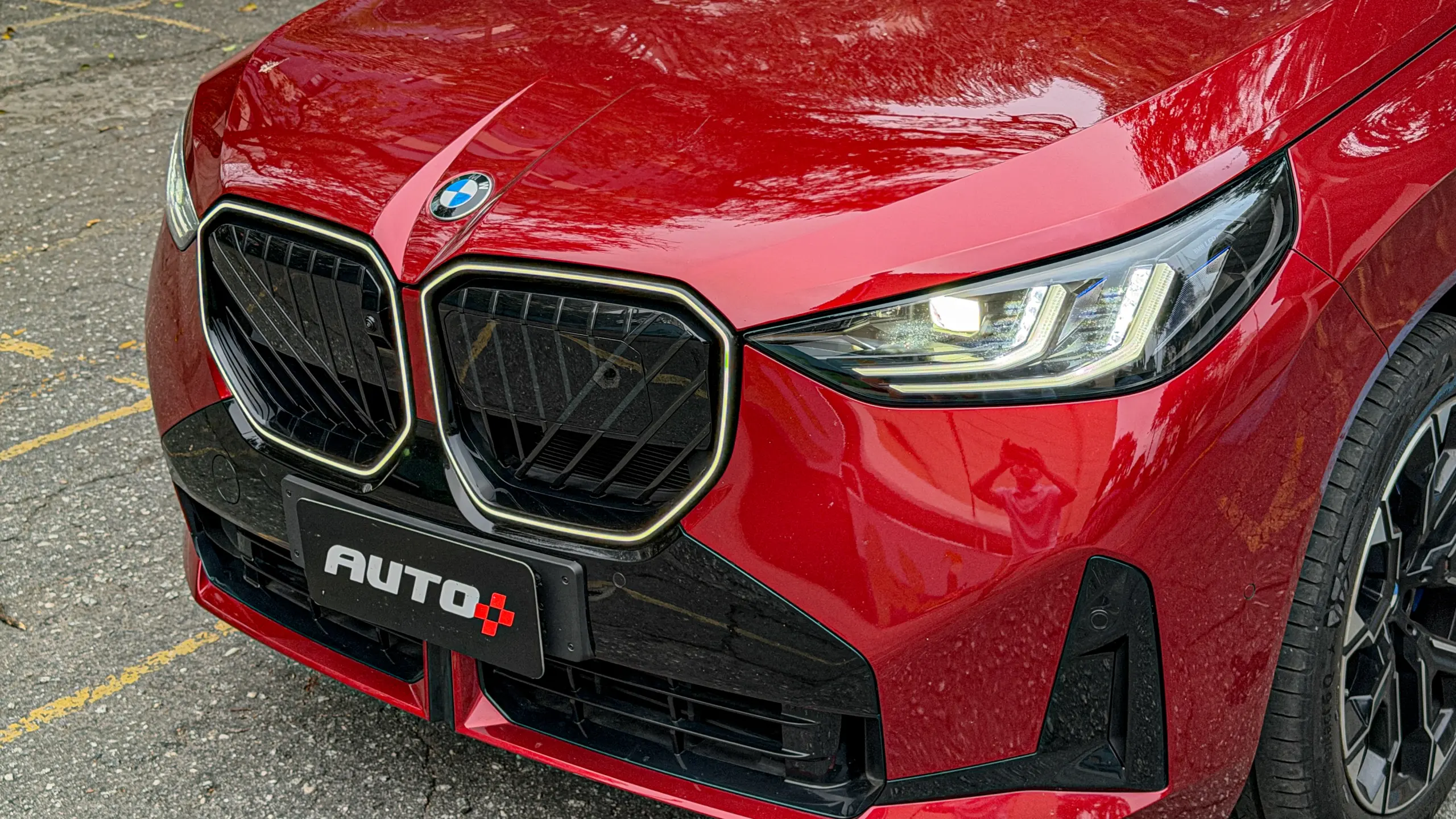 Detalhes do BMW X3 estático na cor Vermelho Fire no asfalto para teste e avaliação