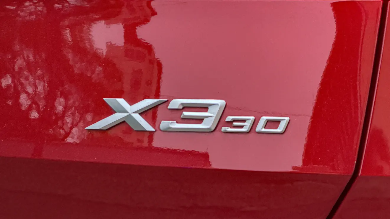 Detalhes do BMW X3 estático na cor Vermelho Fire no asfalto para teste e avaliação