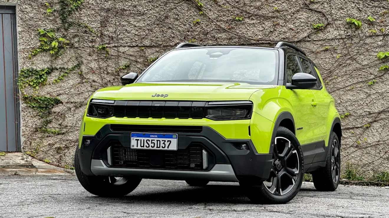 Jeep Avenger Limited verde parado de frente com muro de cimento e plantas ao fundo