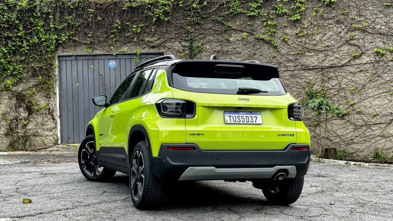 Jeep Avenger Limited verde parado de traseira com muro de cimento e plantas ao fundo