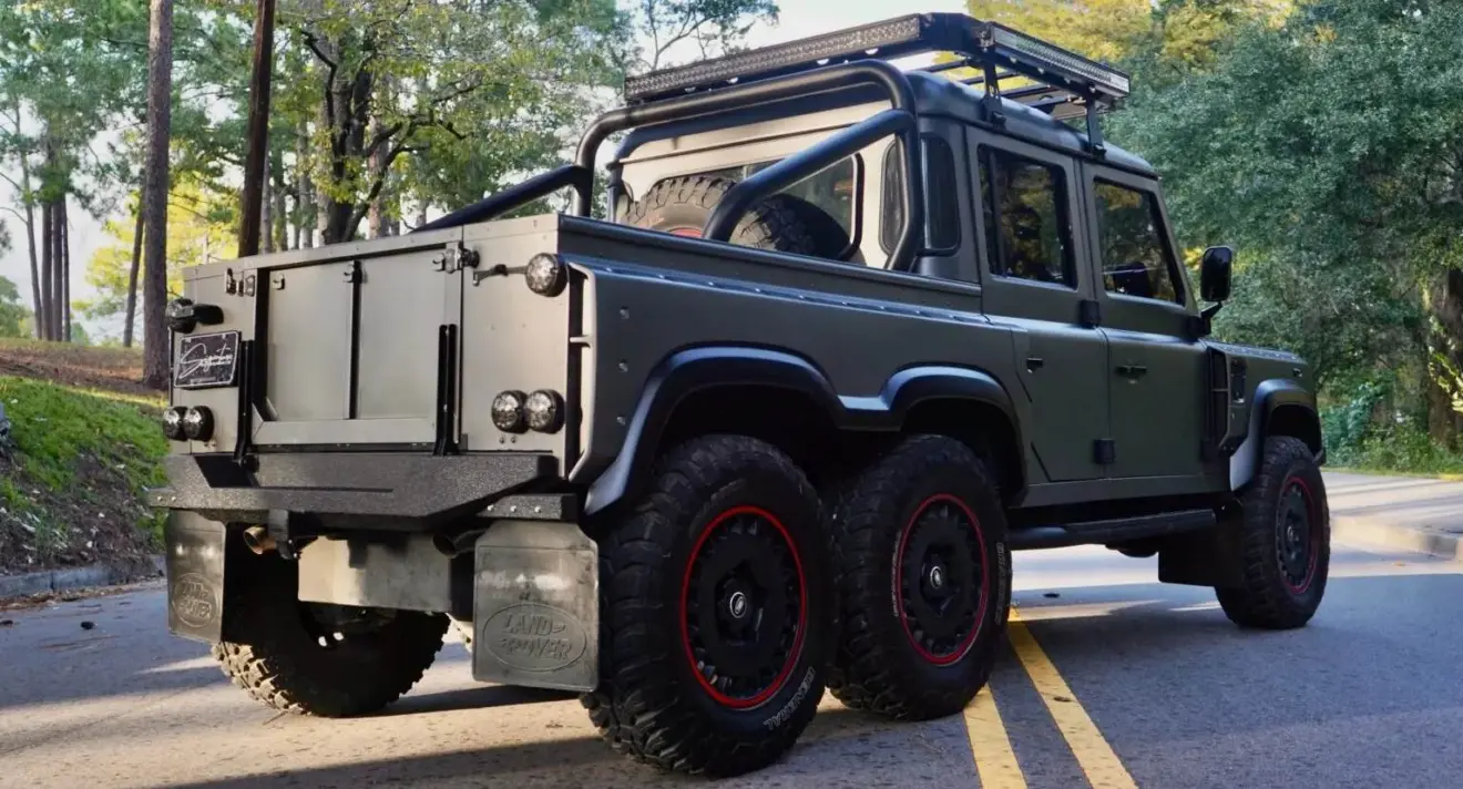 Land Rover Defender 6x6 cinza parado de traseira